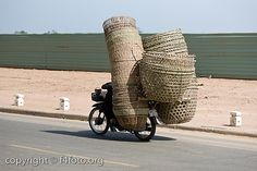 a man riding a motorcycle with stacks of baskets on the back of it's head