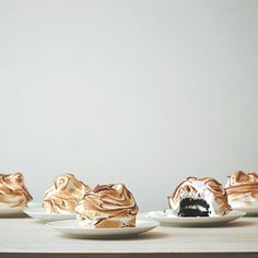 three white plates topped with desserts on top of a wooden table next to each other