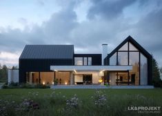 a modern house with large windows and lots of grass in the front yard at dusk