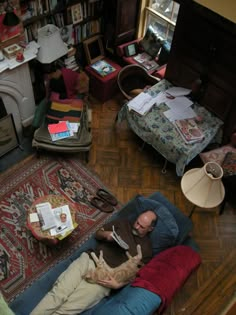 a man laying on top of a blue couch in a living room next to a fire place