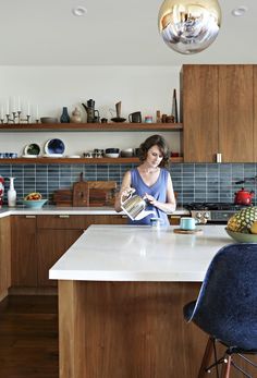 a woman is sitting at the kitchen counter and reading a book while drinking from a mug