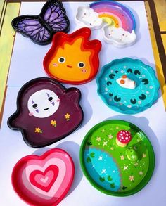 colorful plates with different designs on them sitting on top of a white surface next to a butterfly