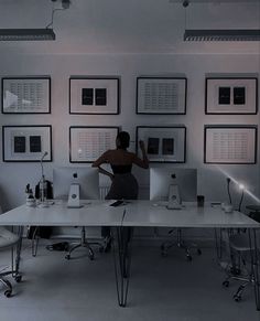 a woman standing in front of a desk with multiple computer monitors on top of it