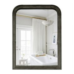 a bath tub sitting next to a window in a white bathroom under a chandelier