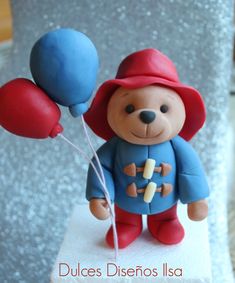 a teddy bear holding two balloons on top of a table