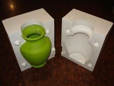 two white and green vases sitting on top of each other