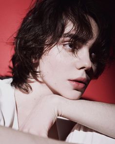 a close up of a person wearing a white shirt and posing for the camera with her hand on her shoulder