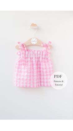 a pink and white checkered dress hanging on a wooden hanger