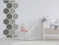 a baby's room with a white rocking chair and grey hexagonal wall decals