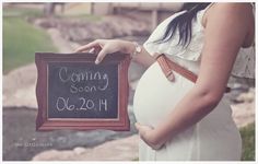 a pregnant woman holding a chalkboard with the words coming soon on it