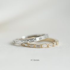 two wedding bands with baguettes and diamonds in them on a white tablecloth