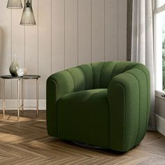 a green chair sitting on top of a hard wood floor next to a table and lamp