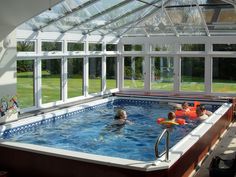 people in an indoor swimming pool surrounded by glass walls and windows with sliding doors on both sides