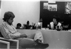 an old black and white photo of two people sitting at a counter in front of a mirror