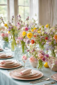 a long table with plates and flowers in vases on top of it, along with other place settings