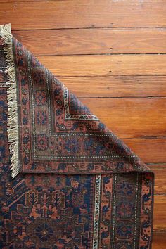 an old rug is laying on the floor next to a wood paneled wall,