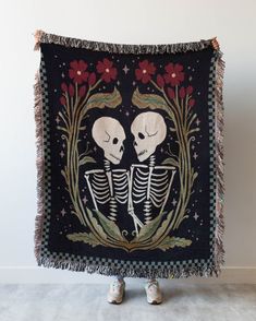 two skeletons sitting in front of a black wall hanging