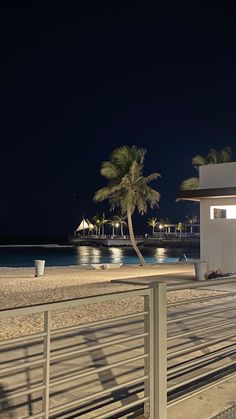 a white building on the beach at night with palm trees and lights in the background