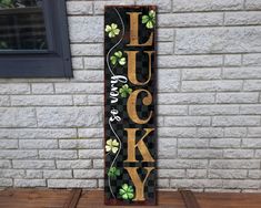 a wooden sign that says luck and lucky with shamrocks on it in front of a brick wall