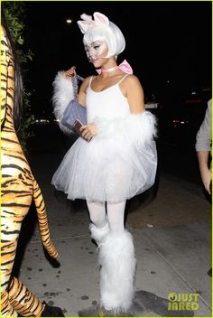 a woman dressed up as a cat with white hair and tutu is walking down the street