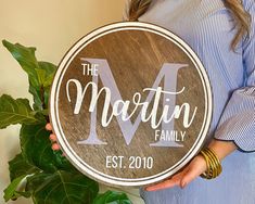 a woman holding a wooden sign that says the martin family