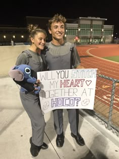 two people standing next to each other holding a sign