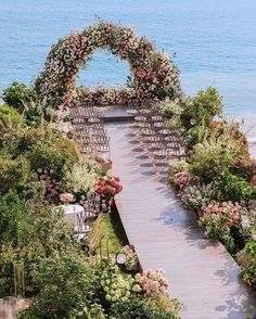 an outdoor ceremony set up with flowers and greenery on the steps leading to the ocean