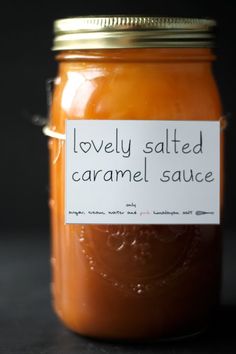 a jar filled with caramel sauce sitting on top of a table next to a black background