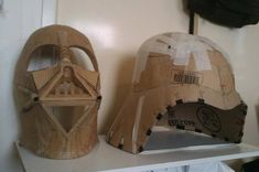 two wooden helmets sitting on top of a white shelf