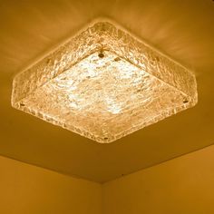 a square light fixture hanging from the ceiling in a room with yellow walls and flooring