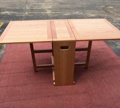 a wooden table sitting on top of a red rug next to a parking lot with no one around it