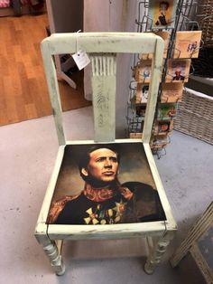 a chair with a painting on the back of it's seat in a store