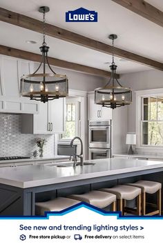 a kitchen with white cabinets and gray countertops, two pendant lights hanging over the island