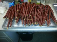 several sausages are on a metal tray in the kitchen sink, ready to be cooked