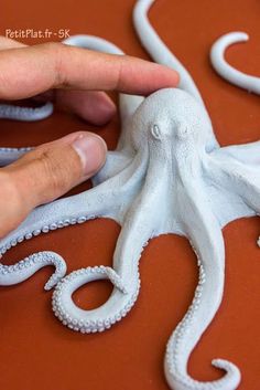 a hand touching an octopus sculpture on top of a table