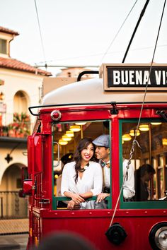 a man and woman sitting in the back of a red trolley