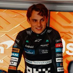 a young man is smiling while standing in front of a wall with logos on it