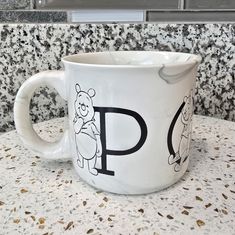 a white coffee cup with winnie the pooh drawn on it sitting on a counter