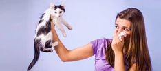 a woman holding a cat and blowing it's nose