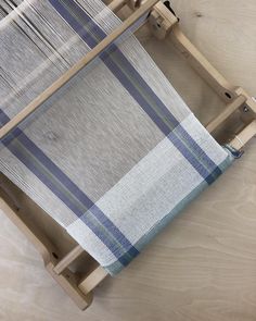 a blue and white striped loom on a wooden stand