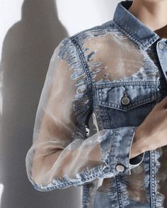 a woman wearing a jean jacket with holes on it