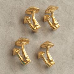 four gold colored knobs with mushrooms on them sitting on the ground next to each other