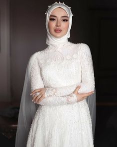 a woman wearing a white dress and veil with her arms crossed, posing for the camera