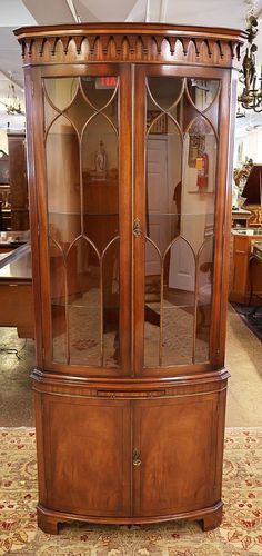 a wooden china cabinet with glass doors on the top and bottom, sitting in a living room