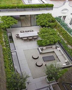 an aerial view of a patio with seating and trees in the center, surrounded by greenery