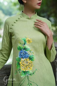 a woman wearing a green dress with flowers painted on the front and back of it