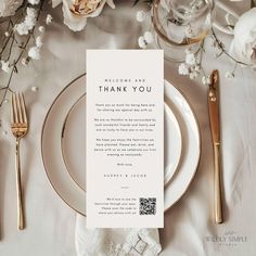 a table set with white and gold place settings, silverware, and napkins