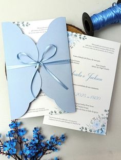 a wedding card with a blue ribbon on it next to a spool of thread