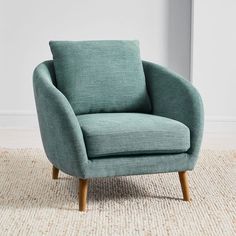 a blue chair sitting on top of a rug in front of a white wall and floor