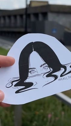 a person holding up a sticker with the image of a woman's face